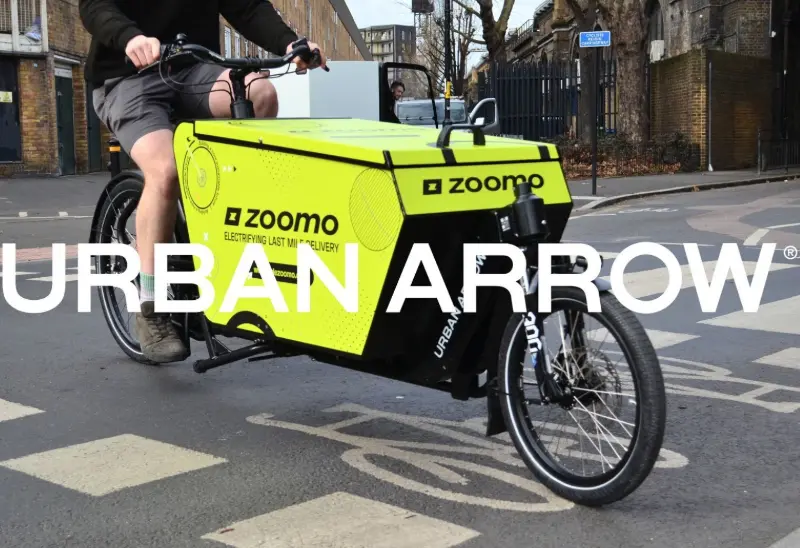This bright lime‑green custom cargo box, co‑branded between Urban Arrow and Zoomo, integrates fleet tracking labels and robust modular compartments.labeled with “Zoomo” and designed for subscription fleets.