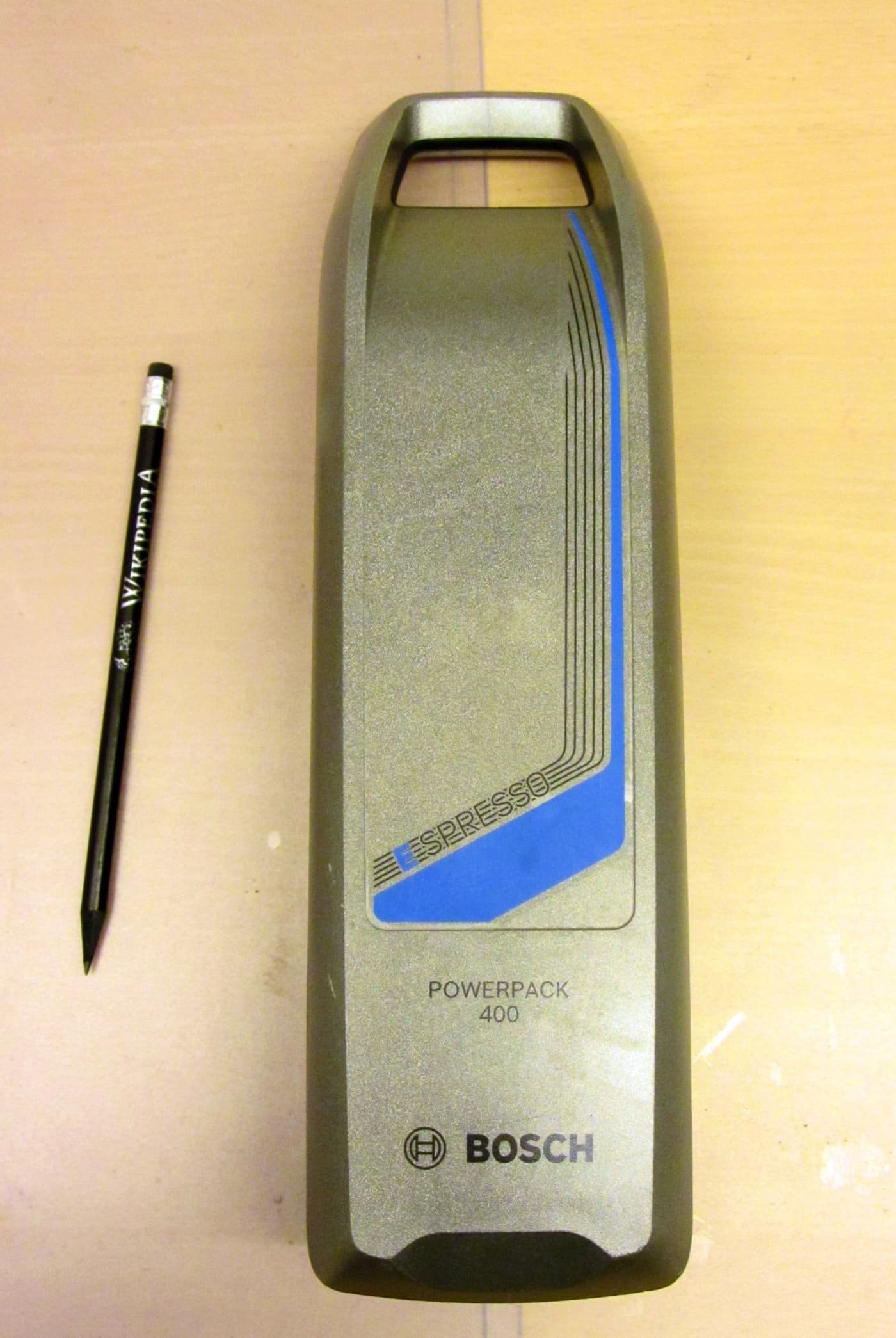 A removable lithium-ion e-bike battery with a pencil for scale